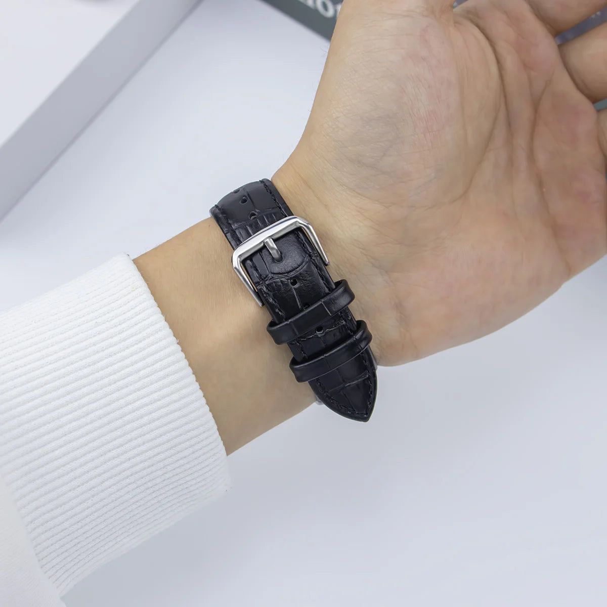 Close-up of a person's wrist wearing a black Garmin leather strap replacement band for smartwatch.