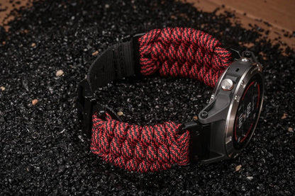 Garmin paracord watch band strap in red and black on textured surface, showcasing its durable sports design and customizable fit.