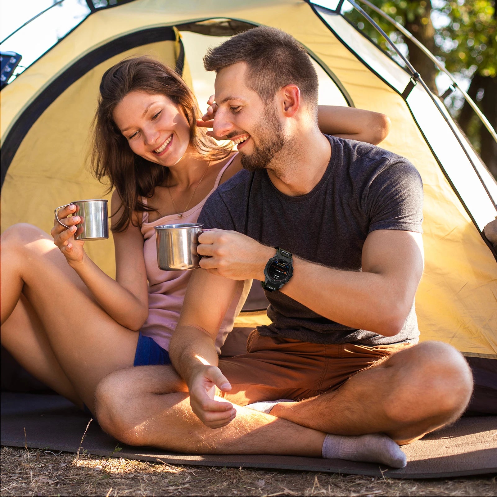 Couple enjoying coffee together in a tent, wearing outdoor gear and showcasing an active lifestyle.