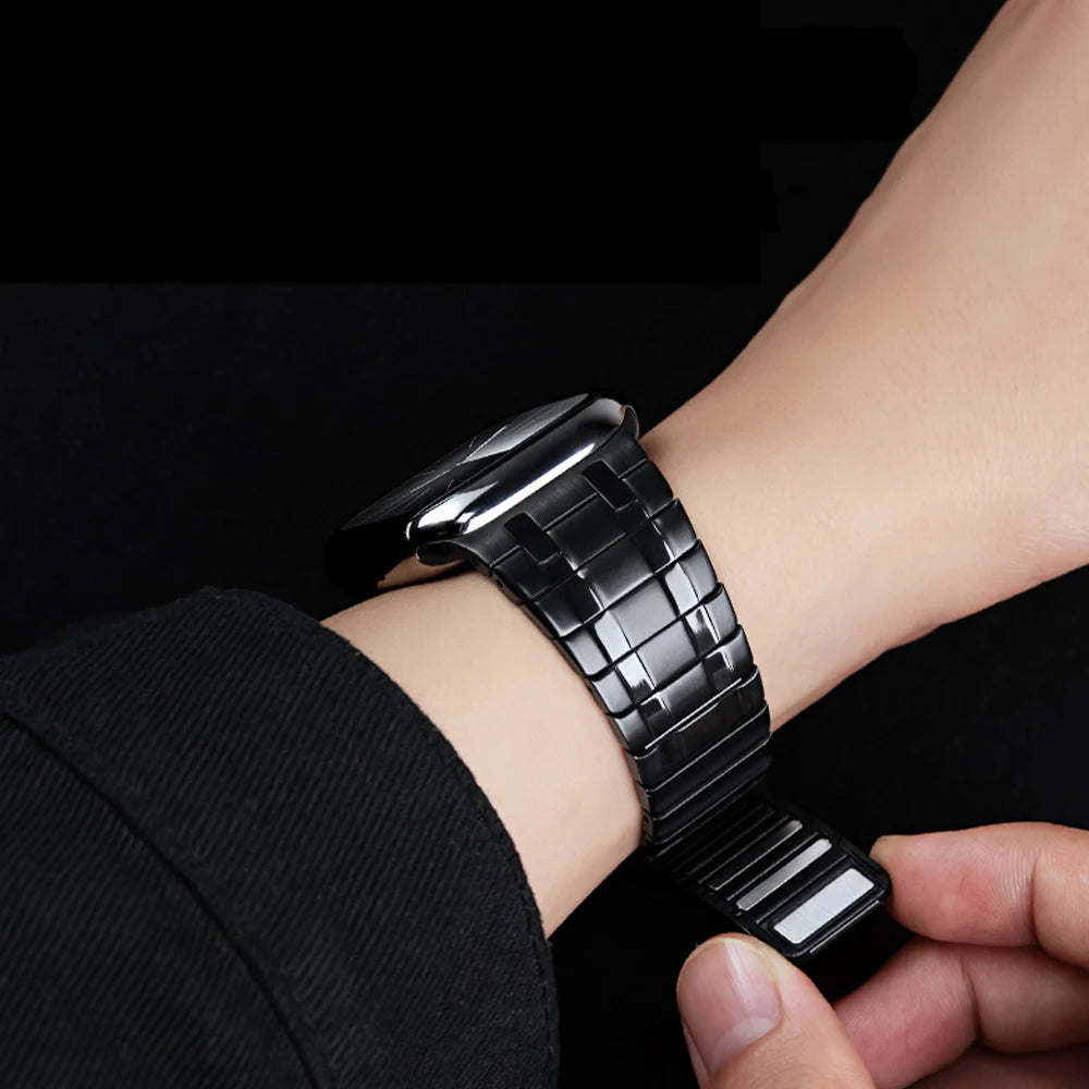 Apple Watch with a magnetic stainless steel band in premium titanium color worn on a wrist.