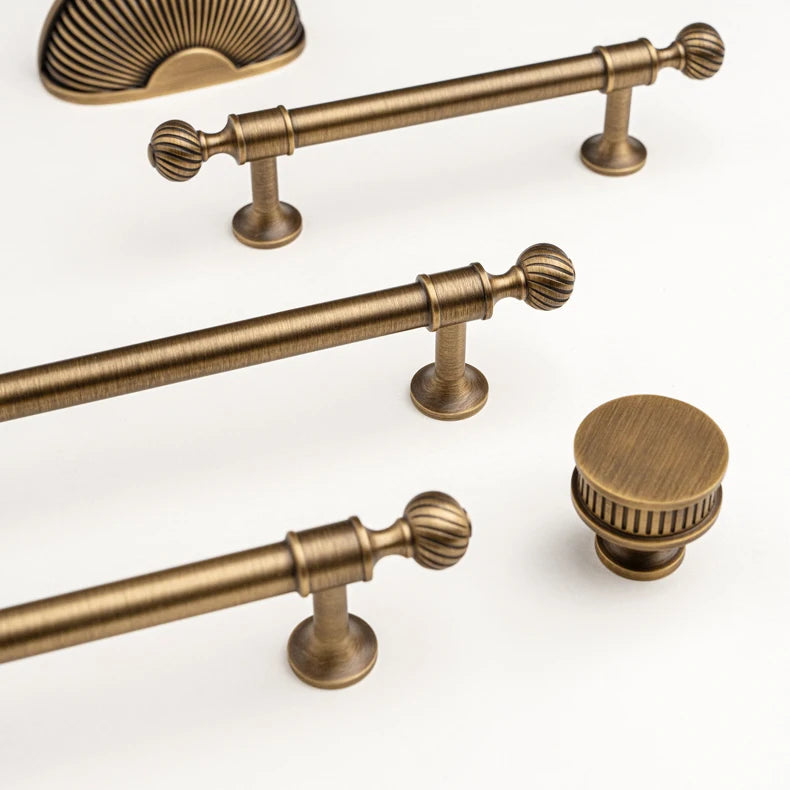 Ribbed solid brass cabinet pulls and a matching round knob in antique brass