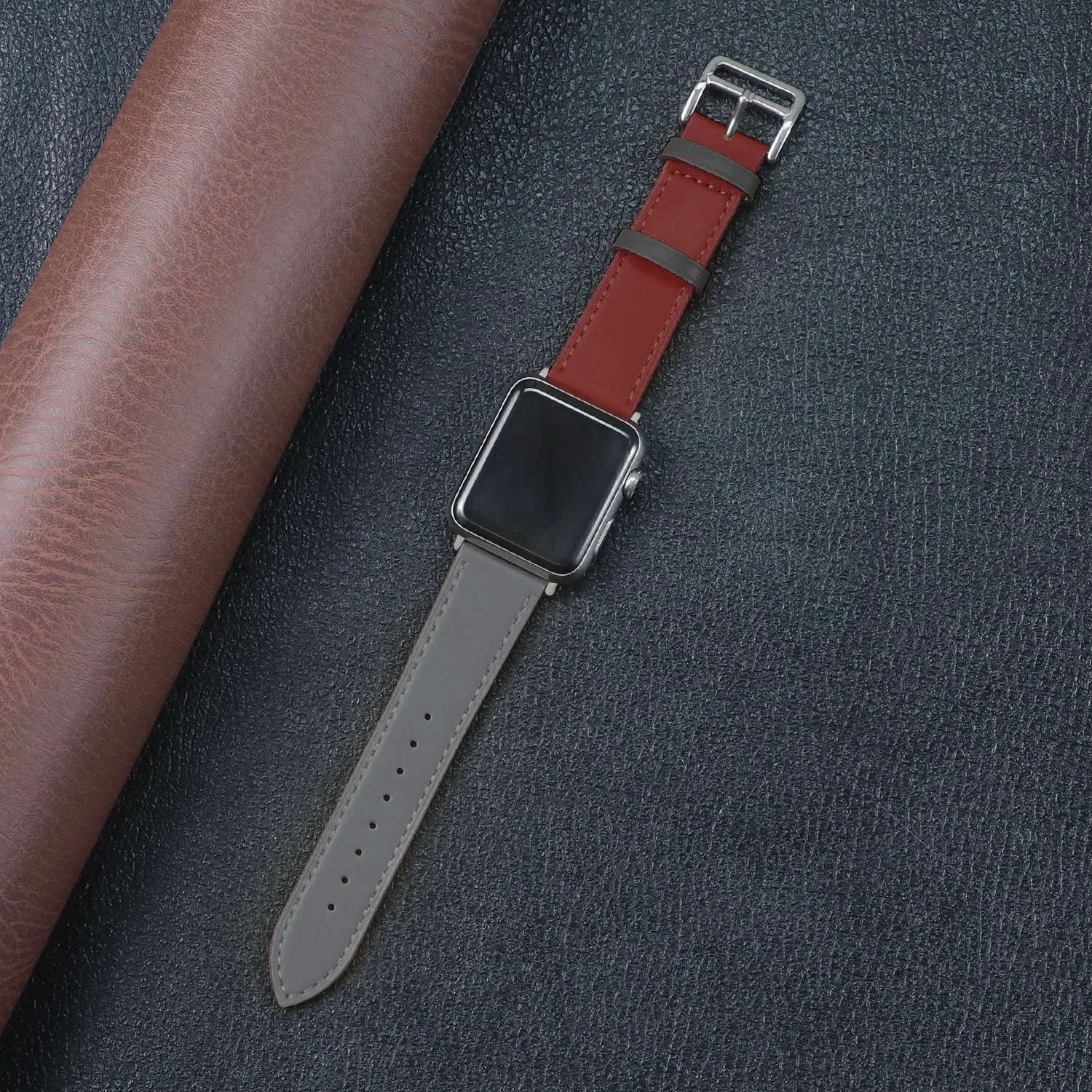 Apple Watch with red and gray fabric band on a textured background, showcasing style and durability.