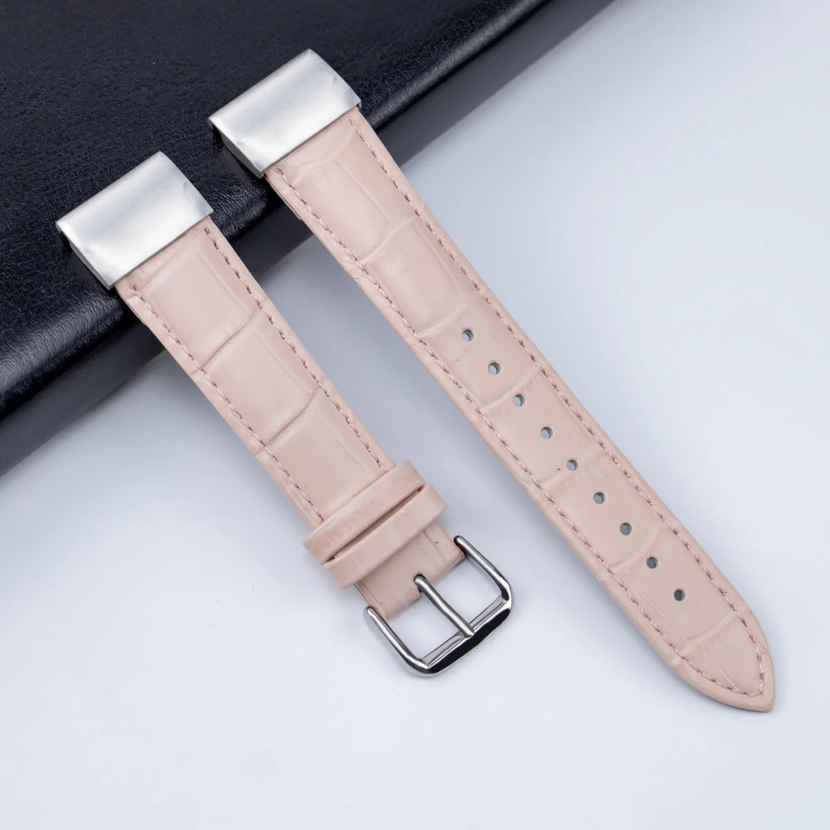 Garmin leather strap in light pink color, showing adjustable band with silver buckle for smartwatch replacement.