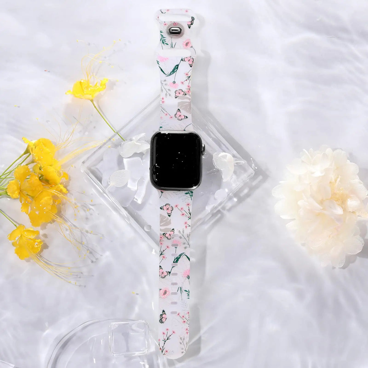 Floral and butterfly strap displayed beside flowers for Apple Watch