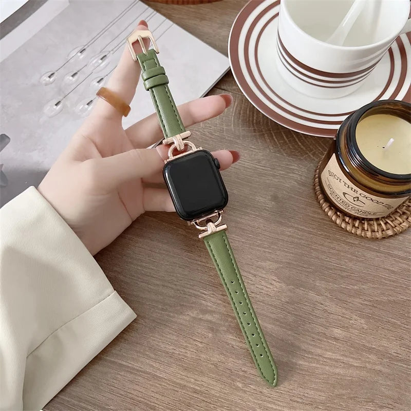 Apple Watch with green genuine leather strap placed on a wooden table next to a candle and coffee cup.
