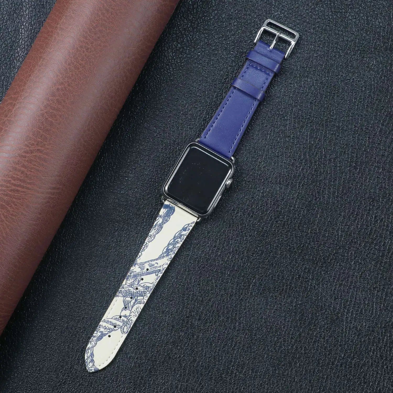 Apple Watch with a unique blue and white design fabric band, placed on a textured black surface.