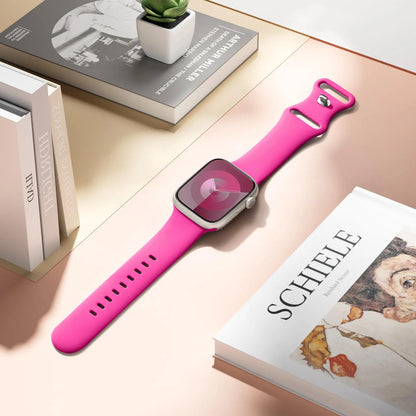 Apple Watch with a pink silicone strap on a stylish table with magazines and a plant.
