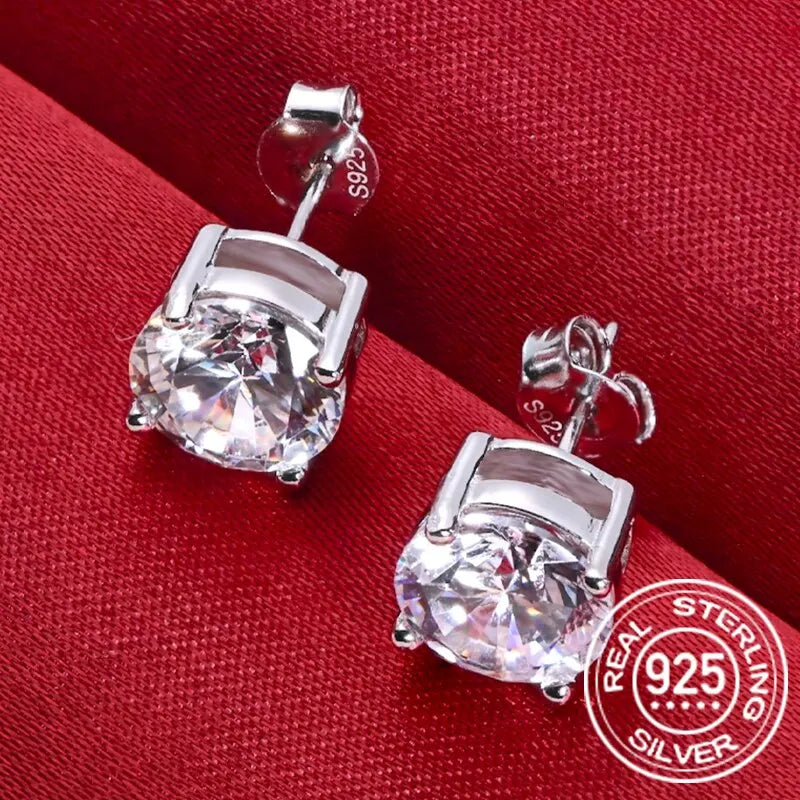 Round Four-Prong Moissanite Stud Earrings in Sterling Silver — Pair on red fabric