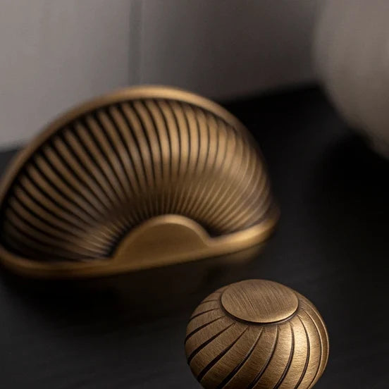 Ribbed Shell solid brass cup pull and a matching ribbed knob in antique brass