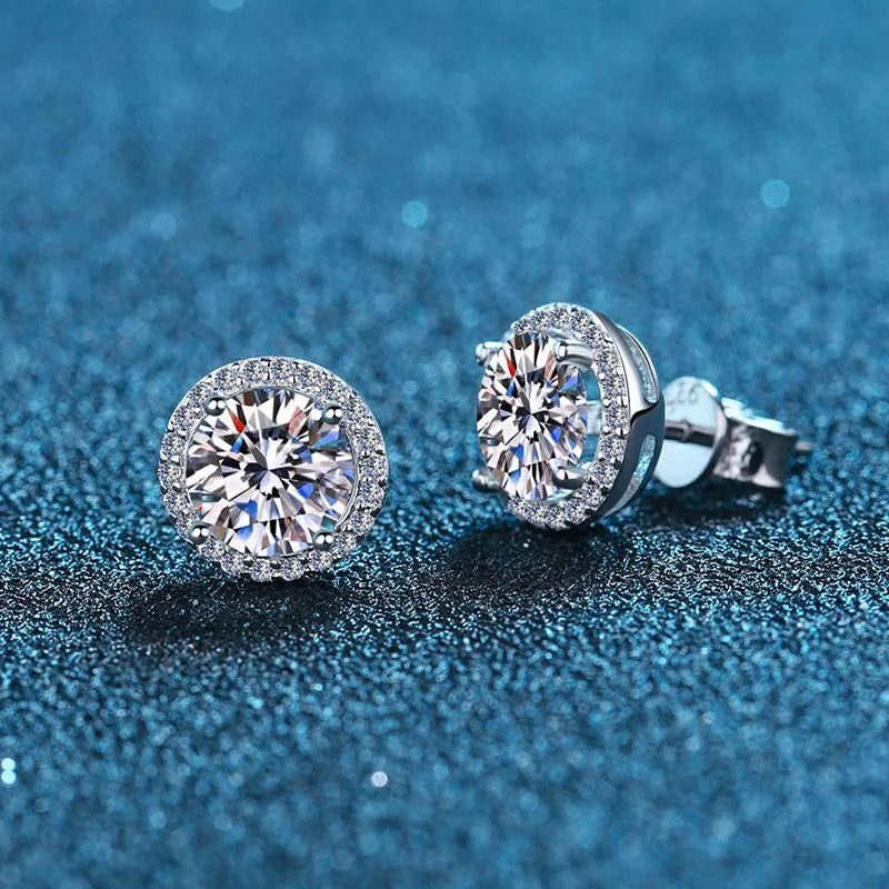 Round Halo Moissanite Stud Earrings in Sterling Silver — Halo pair on blue surface